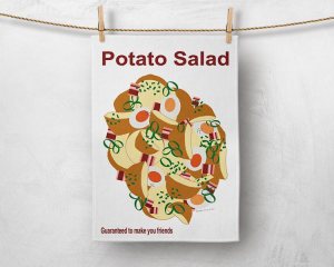 Image of a tea towel pegged with a wooden peg in each top corner, hanging on some twine in front of a concrete looking light grey background. The tea towel has an illustration of potato salad on the middle of it. The salad consists of cut potatoes with the skin on, spring onion, boiled eggs cut in half and small pieces of bacon. At the top of the tea towel are the words 'potato salad' in dark red and at the bottom it says 'guaranteed to make you friends' also in dark red.